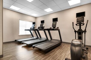 Sala de ginástica com esteiras, bicicleta ergométrica e remo.