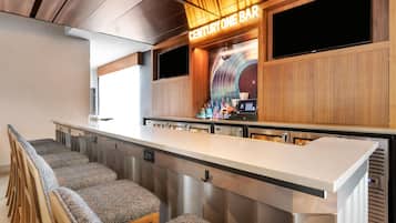 Uma área de bar com balcão, banquetas e um letreiro que diz 'CENTURY ONE BAR'.