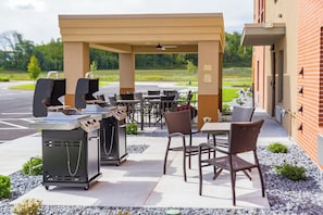 An outdoor patio with barbecue grills, seating, and a brick building in the background. - Candlewood Suites Eau Claire I-94 by IHG (Eau Claire)