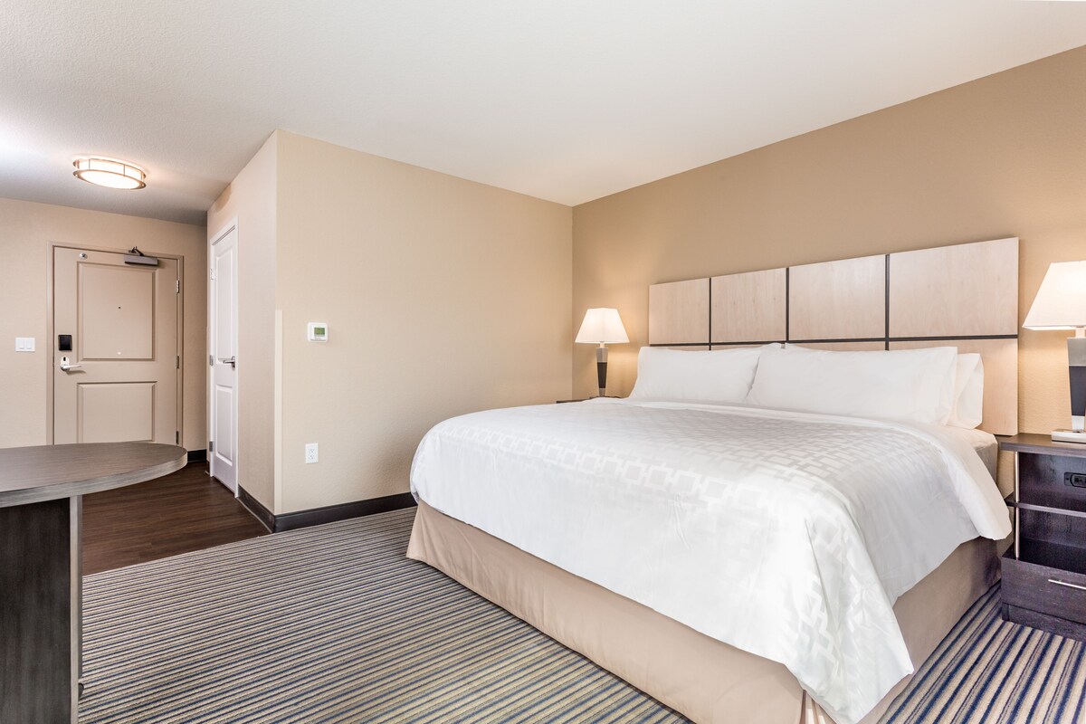 Ein Hotelzimmer mit einem großen Bett, zwei Nachttischlampen, einem Schreibtisch und einem Sessel.
