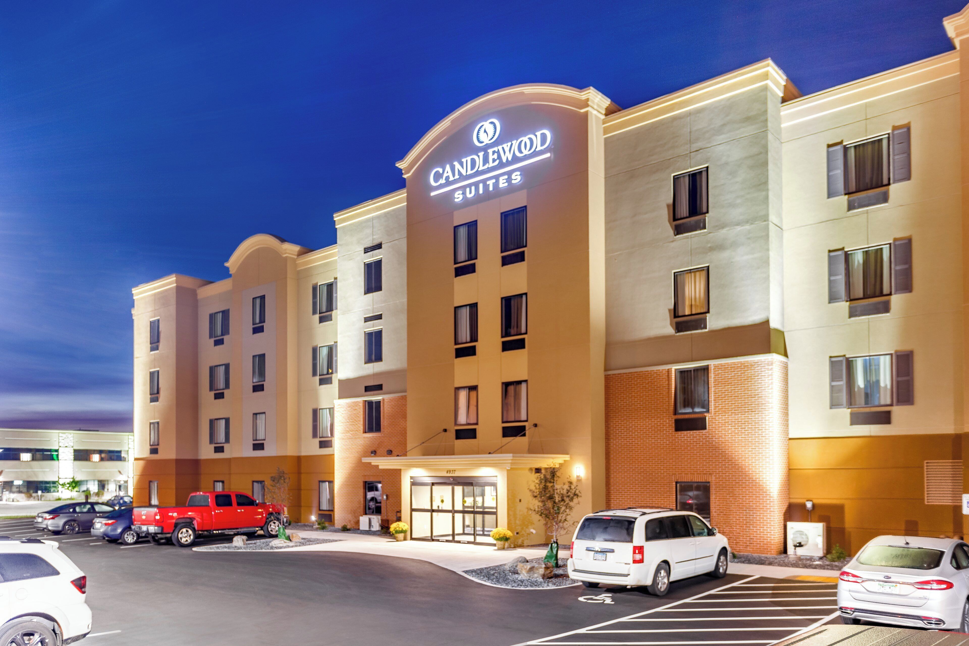 A hotel with a prominent sign, multiple parking spaces, and a well-lit entrance.