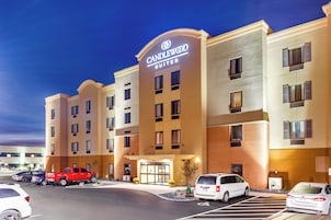 Un hotel con un letrero llamativo, varios espacios de estacionamiento y una entrada bien iluminada.