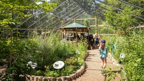 A greenhouse with a wooden structure, a gravel path, and various plants. - Candlewood Suites Eau Claire I-94 by IHG (Eau Claire)