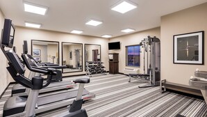A gym with cardio equipment, weight machines, and mirrors.