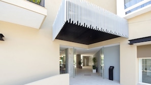 A modern building entrance with a glass door, a staircase, and a black trash bin. - Designer Condo in Zona Romantica (Puerto Vallarta)