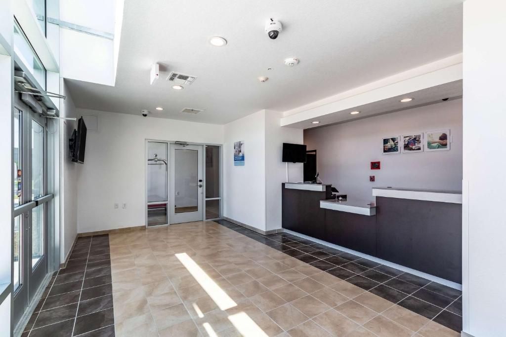 A hotel lobby with a reception desk, a coat rack, and a door leading to the rooms.