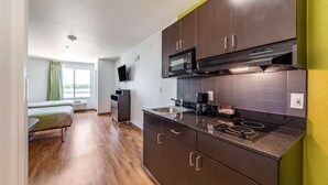 A compact kitchen with dark cabinets, a microwave, and a gas stove. - Studio 6 San Marcos, TX (San Marcos)