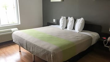 A neatly made bed with a striped blanket, a bedside table with a lamp, and a window with blinds.