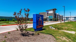 A hotel sign with the name 'studio 6 extended stay' and a modern building in the background. - Studio 6 San Marcos, TX (San Marcos)