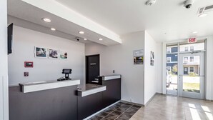A reception area with a counter, a door marked "BUSINESS ONLY," and an exit sign. - Studio 6 San Marcos, TX (San Marcos)