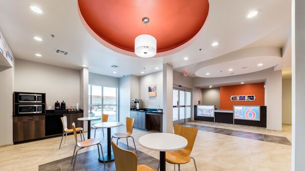 A modern hotel lobby with a reception desk, seating area, and a kitchenette. - Motel 6 Fort Worth, TX - North - Saginaw (Fort Worth)
