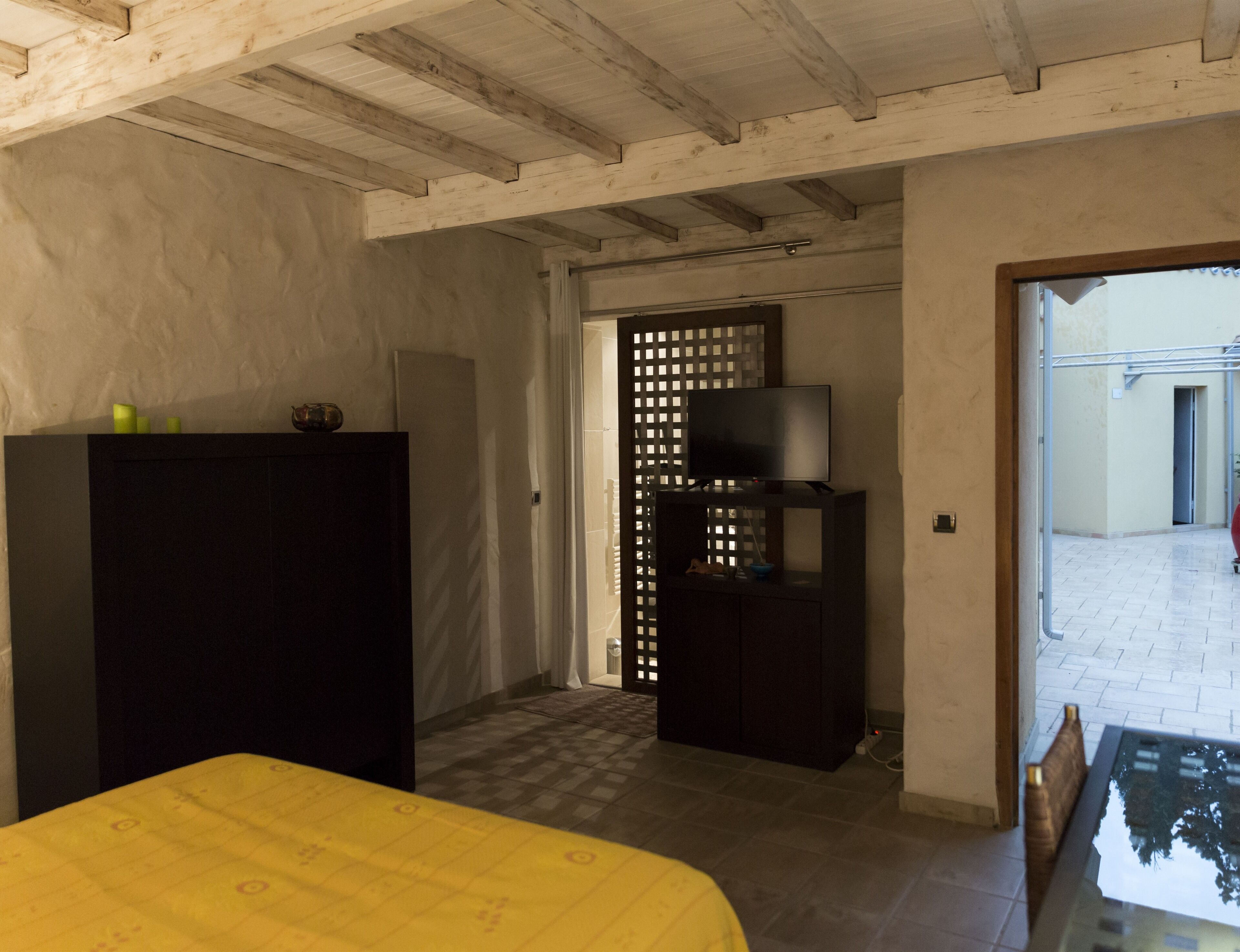 Una camera con un letto, una televisione su un mobile, un armadio e una porta che dà su uno spazio all'aperto.