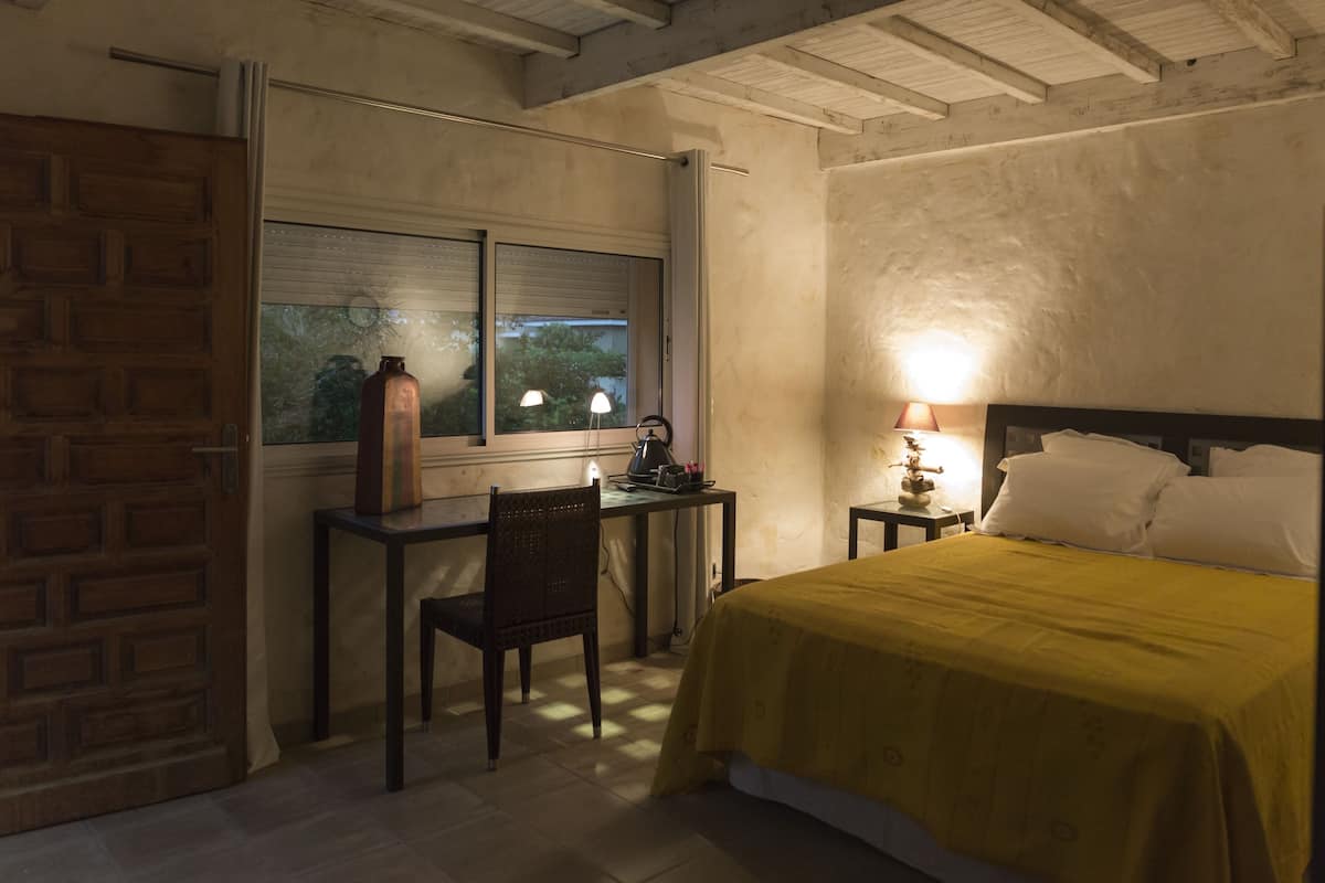 A bedroom with a bed, a desk, and a chair.