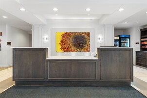 Un área de recepción de diseño moderno, con un mostrador central y una gran obra de arte abstracta en la pared.