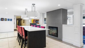 Una cocina moderna con una isla central, una chimenea y un área de comedor con sillas.