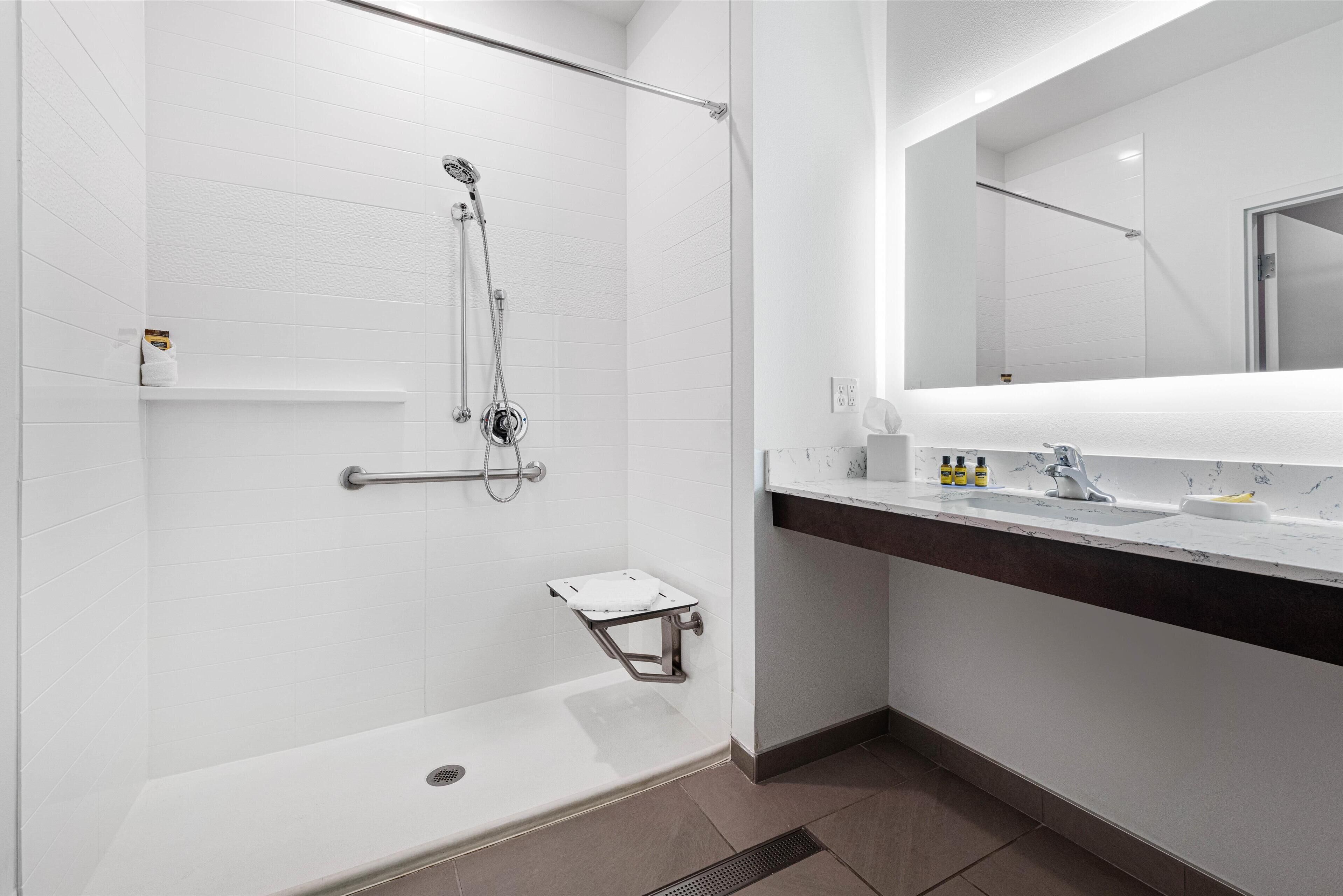 A modern bathroom with a walk-in shower, a vanity with a mirror, and a toilet.
