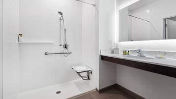 A modern bathroom with a walk-in shower, a vanity with a mirror, and a toilet.