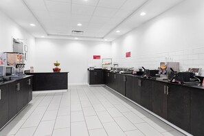 A modern kitchen with dark cabinets, white tiled floors, and various appliances. - Best Western Plus New Richmond Inn & Suites (New Richmond)