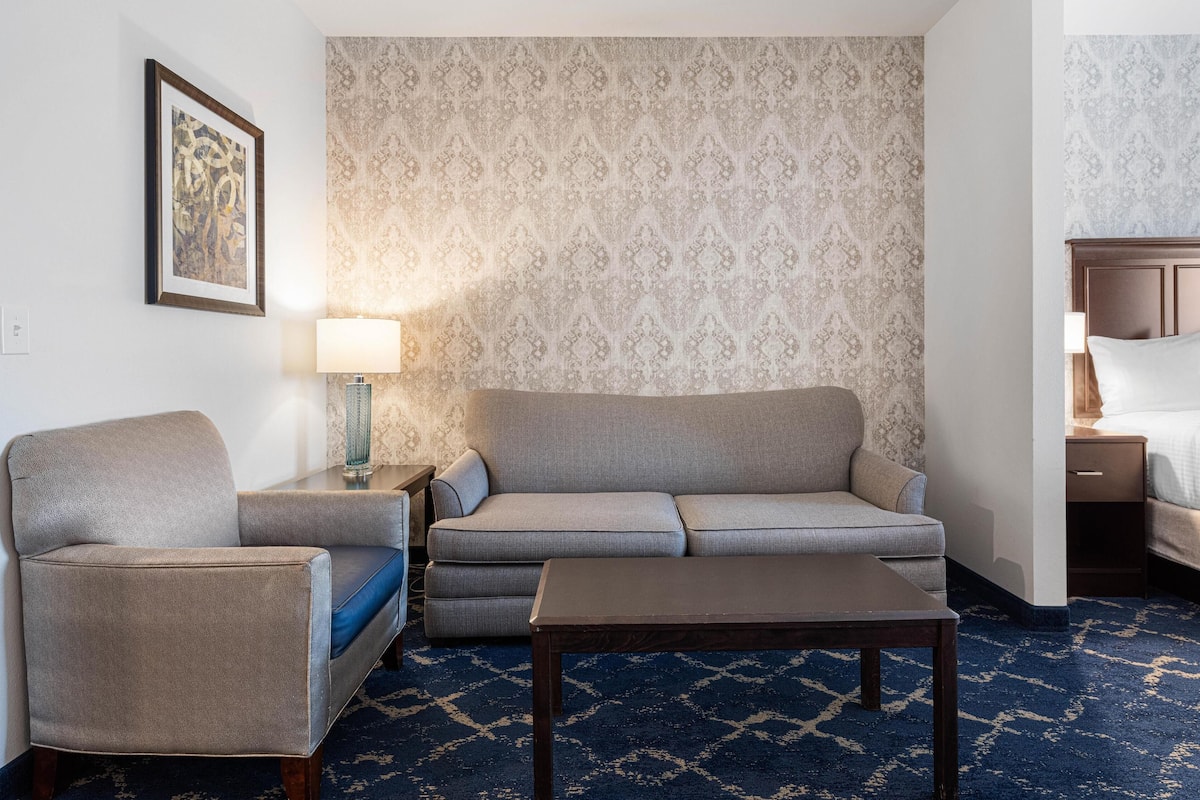 Hotellihuone, jossa on sohva, nojatuoli ja pieni pöytä.