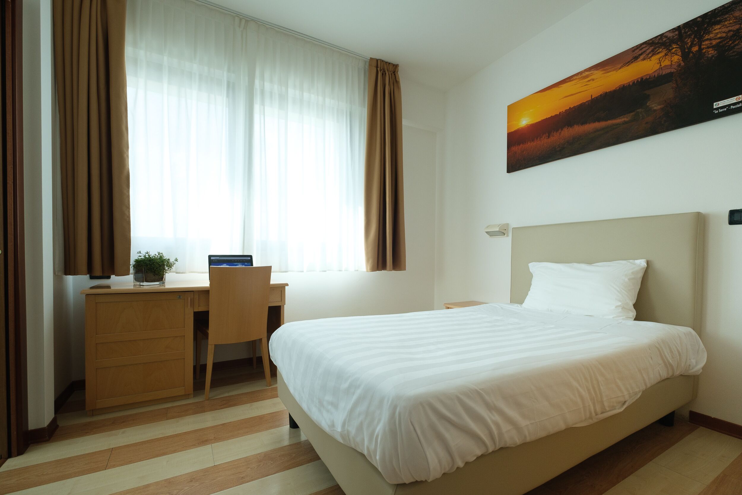 A hotel room with a bed, a desk, and a chair.