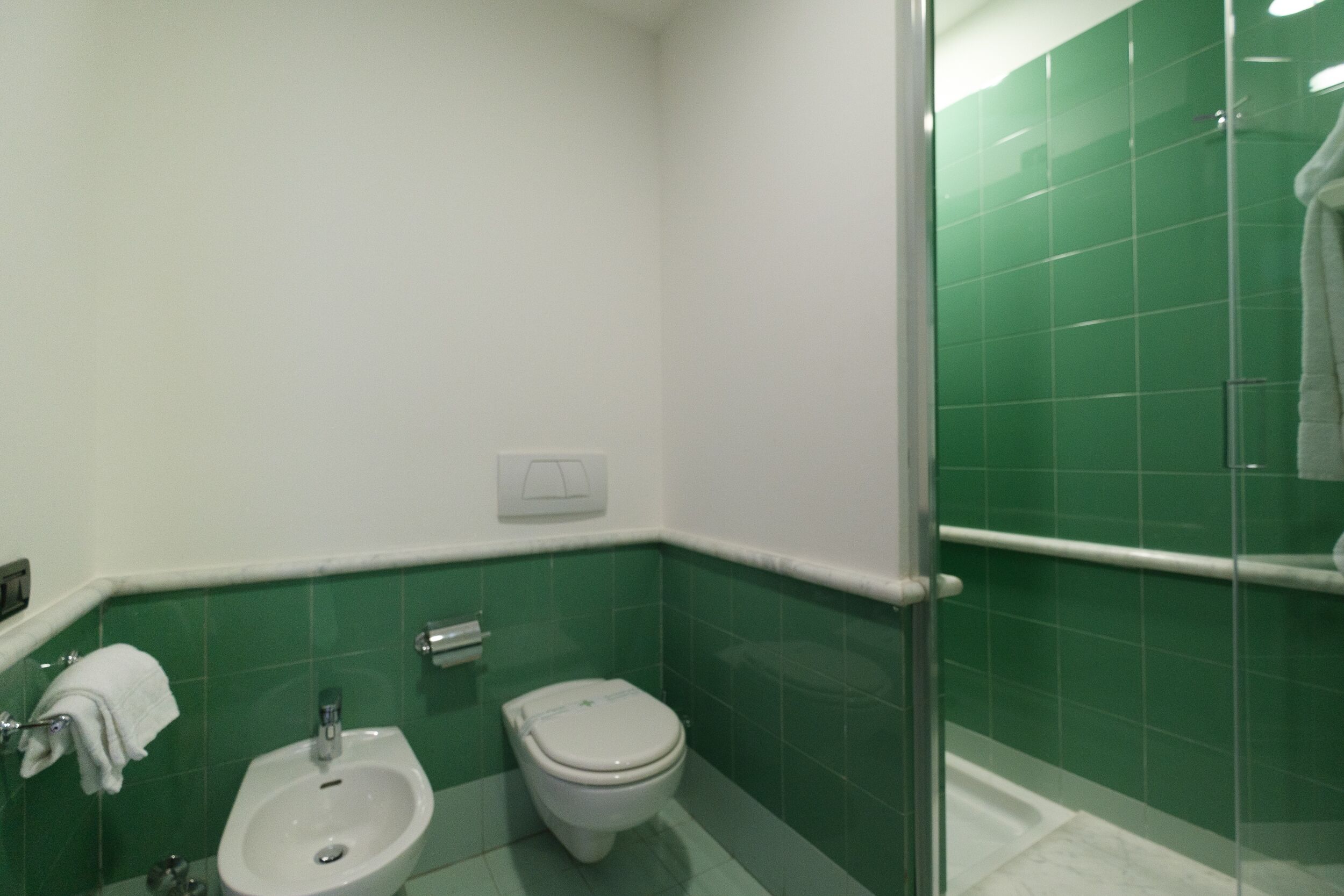 Un bagno con bidet, WC e box doccia in vetro.