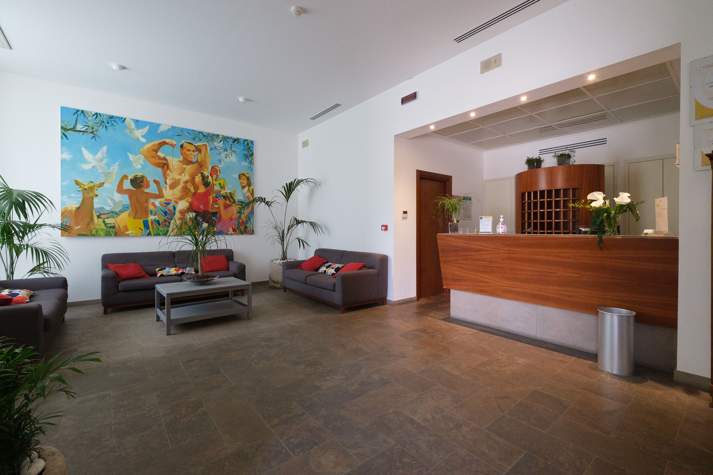 Un vestíbulo moderno con mostrador de recepción, dos sofás, una mesa de centro y un mural grande en la pared.