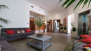 A spacious living area with a grey sofa, a coffee table with a plant, and a grey couch with red cushions. - Hotel Portavaldera (Peccioli)