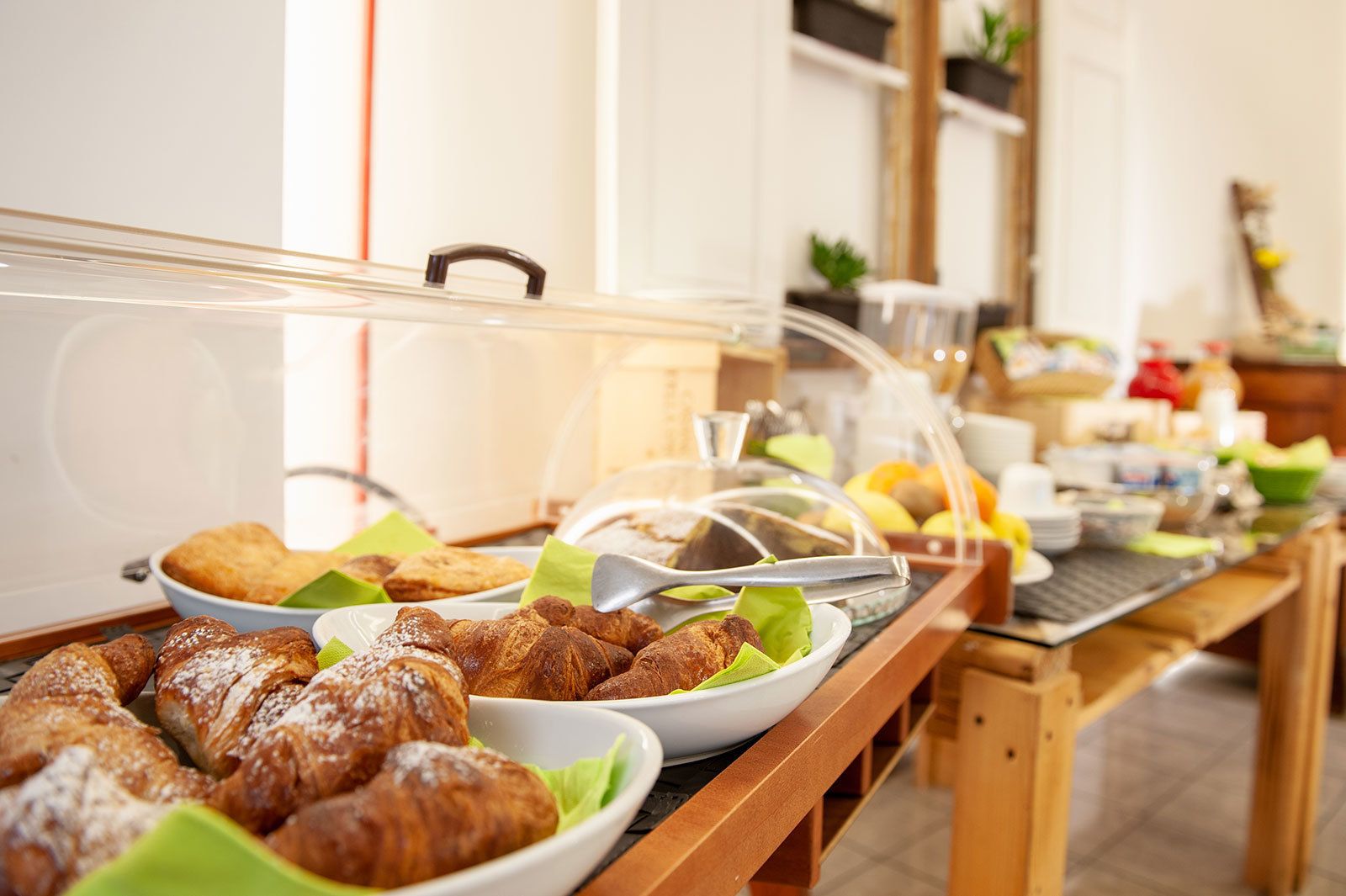 Ein Buffet mit verschiedenen Gebäcken und Speisen, darunter Croissants und einer Auswahl an Früchten.