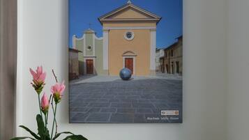 Une pièce dans laquelle on peut voir un tableau représentant une église, une petite plante en pot, un plateau avec des croissants, des tasses et une carafe.