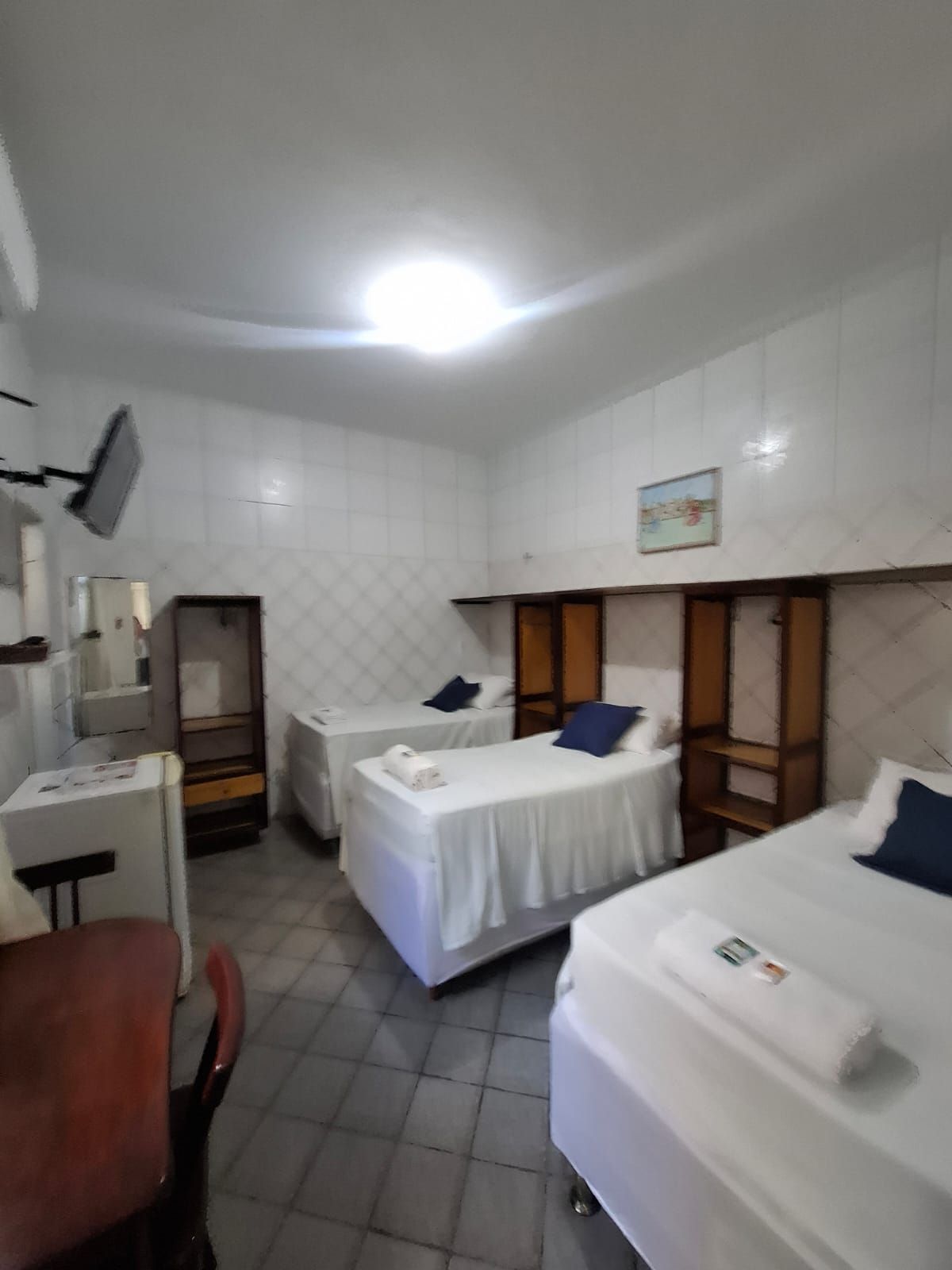 A hotel room with two single beds, a desk, a chair, and a television mounted on the wall.