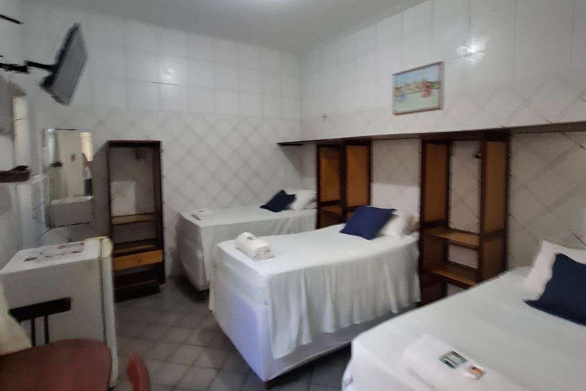 Una habitación de hotel con dos camas individuales, un escritorio, una silla y un televisor montado en la pared.