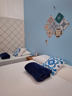 A hotel room with a bed, a nightstand, a wall-mounted phone, and decorative tiles. - Hotel Ilha dos Azulejos (São Luís)
