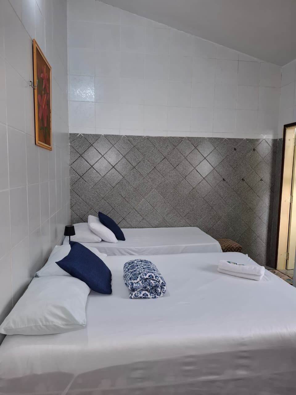Habitación de hotel con cama, cabecera, un cuadro colgado en la pared y una puerta.