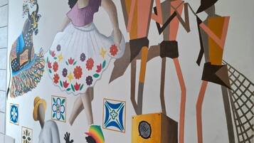 A mural with cultural figures and symbols, including a peacock, a woman in a dress, and a man with a guitar.