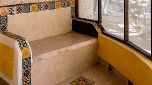 A room with a window, a woven ceiling light, a tiled bench, and a patterned tile border. - Antigua Lodge (El Cuyo)