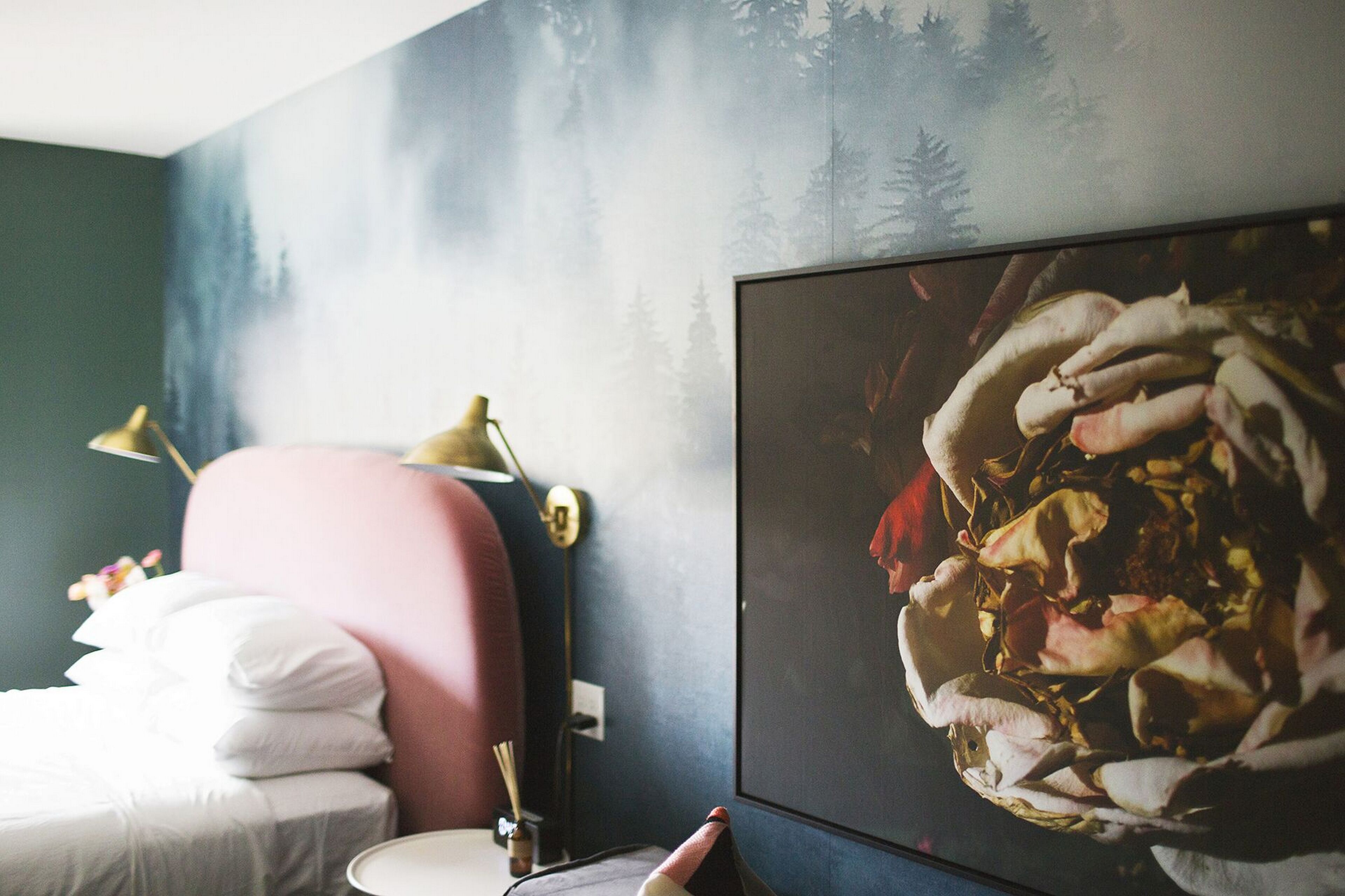 Une chambre à coucher avec un lit, un bureau, une lampe et un grand tableau encadré au mur.