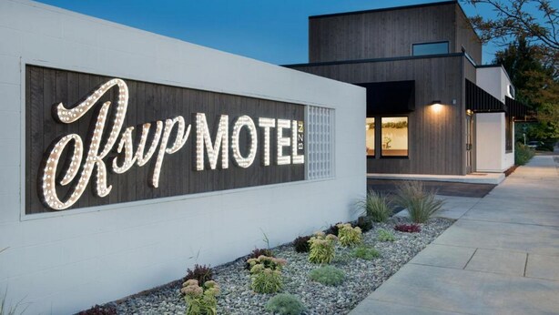 Un motel moderne avec une enseigne lumineuse bien visible, sur laquelle on peut lire « Asup Motel ».
