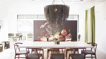 Een eethoek met een witte tafel, rode stoelen en een decoratieve hanglamp.