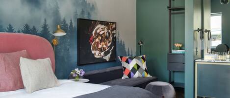 Une chambre moderne avec un lit, un banc, un tableau et une coiffeuse avec des serviettes.