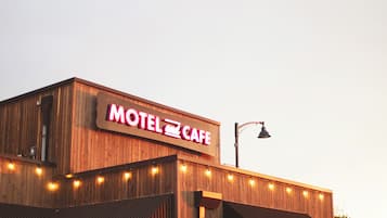 A motel with a prominent sign, a covered outdoor seating area, and a street view.