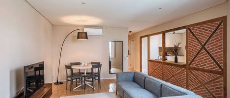 Una sala de estar moderna con un sofá, televisión, mesa de comedor, sillas y un espejo grande.