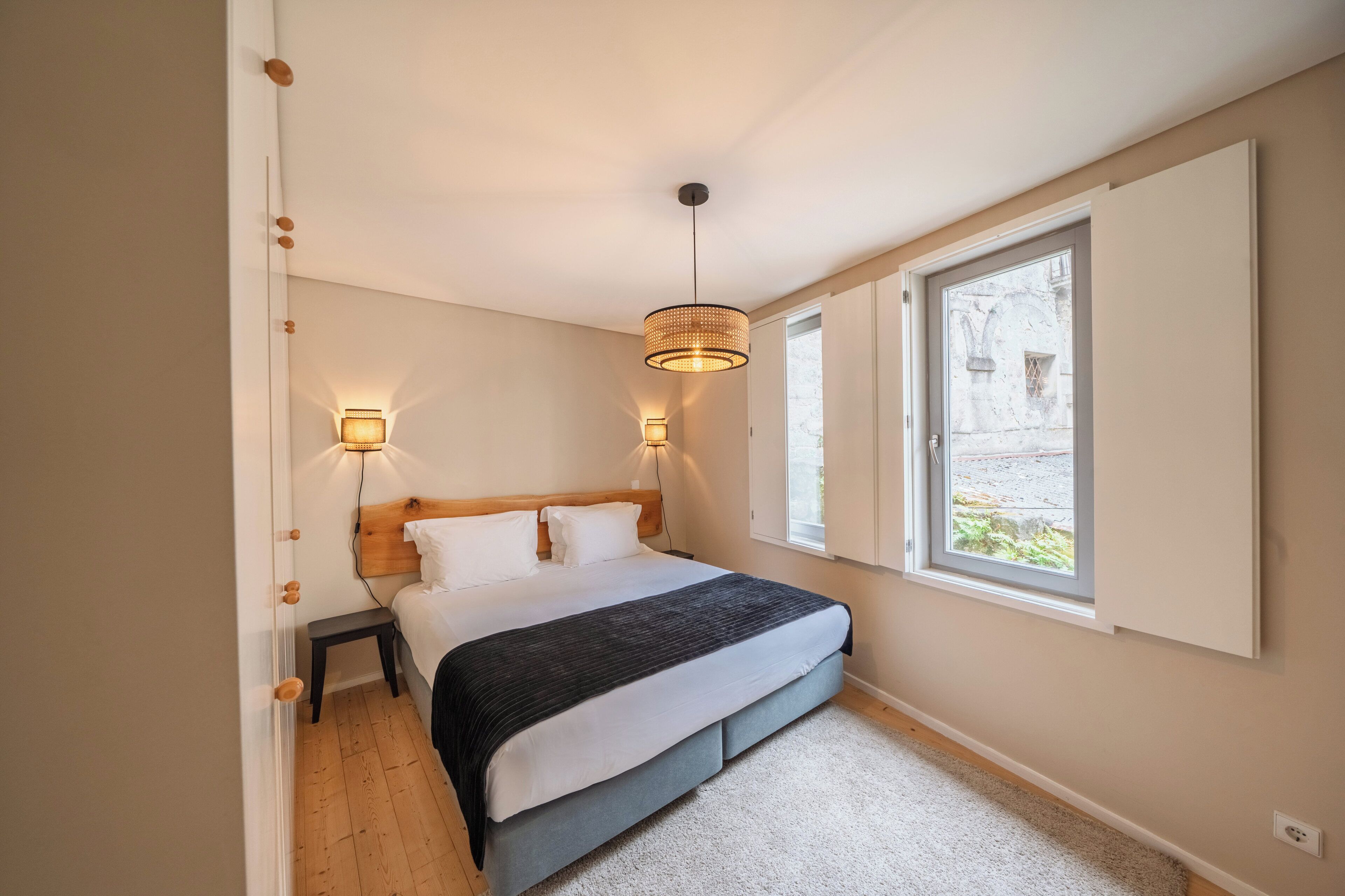 A bedroom with a bed, bedside lamps, a window, and a door.