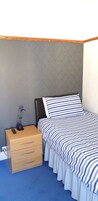 Un dormitorio con cama, mesita de noche, lámpara y cómoda.
