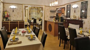 Un restaurant doté d’une longue table à manger dressée pour le repas, d’un bar et d’un comptoir d’accueil.