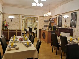 Un restaurante con una larga mesa de comedor lista para una comida, una zona de bar y un mostrador de recepción.