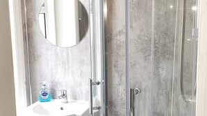 Une salle de bain moderne avec une douche à parois de verre, un lavabo avec un miroir et un porte-serviettes.