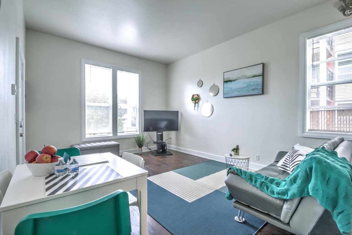 A modern living room with a dining area, a flat-screen TV, and a large window.