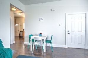 A dining area with a white table and teal chairs, a clock on the wall, and a white door. - Capitol Hill Apartments (Seattle)