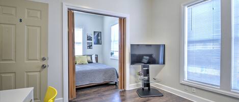 Ein Schlafzimmer mit einem Bett, einem Fernseher und einem Fenster mit Jalousien.