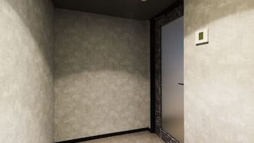 Una habitación con pared texturizada, espejo con marco negro y foco empotrado en el techo.